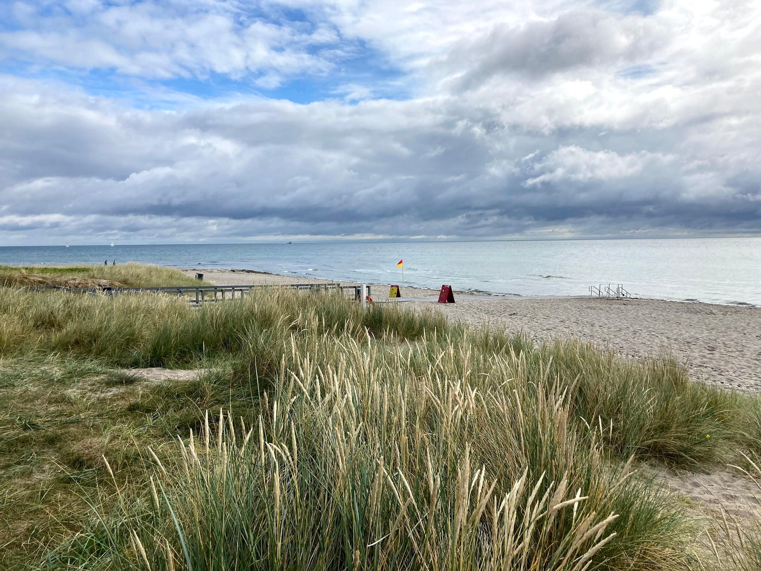 Strand ved Djursland med klitter, hav og strandmåtter under skyet himmel